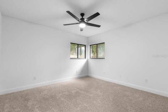 carpeted spare room featuring ceiling fan