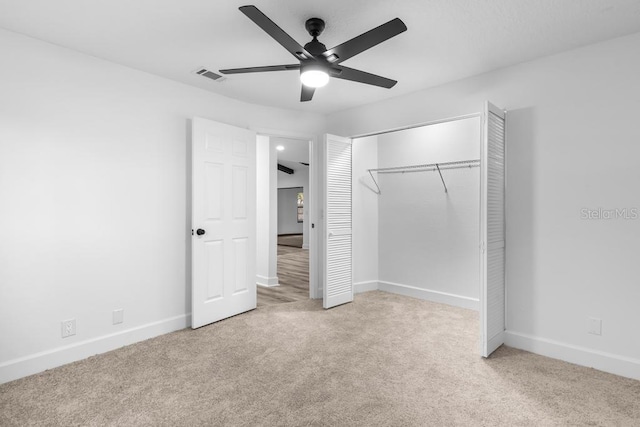 unfurnished bedroom featuring light colored carpet, a closet, and ceiling fan