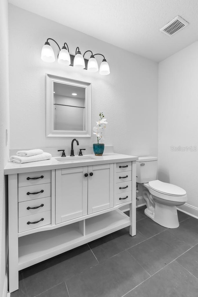 bathroom featuring vanity, tile patterned floors, a textured ceiling, and toilet