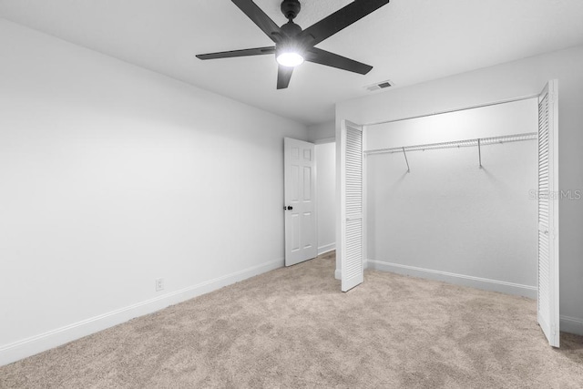 unfurnished bedroom featuring light carpet, a closet, and ceiling fan