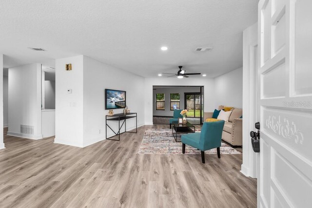 sitting room with ceiling fan, a textured ceiling, and light wood-type flooring