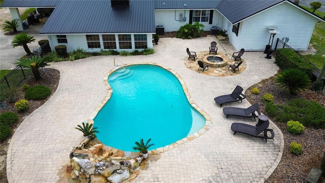 view of pool featuring central AC unit, a patio area, and a fire pit