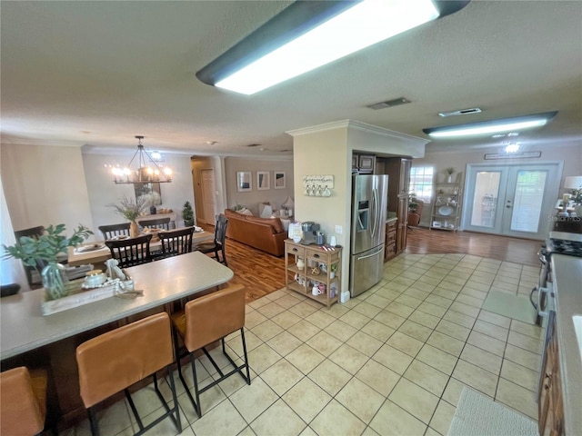 kitchen featuring french doors, a chandelier, stainless steel fridge with ice dispenser, light tile patterned floors, and ornamental molding