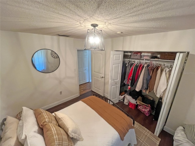 bedroom featuring dark hardwood / wood-style flooring, a chandelier, a closet, and a textured ceiling