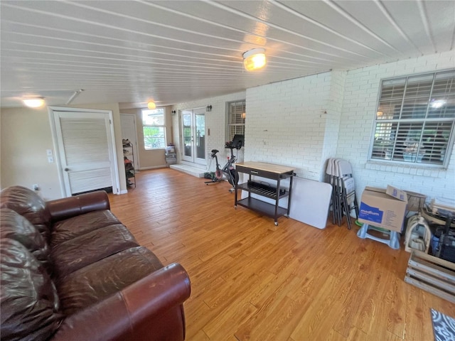 living room with light hardwood / wood-style flooring and brick wall