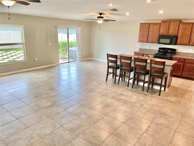 kitchen featuring black appliances, a breakfast bar, light tile patterned floors, and ceiling fan