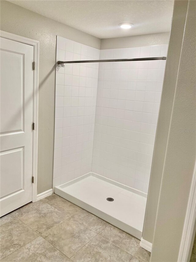 bathroom featuring a textured ceiling, a tile shower, and tile patterned floors