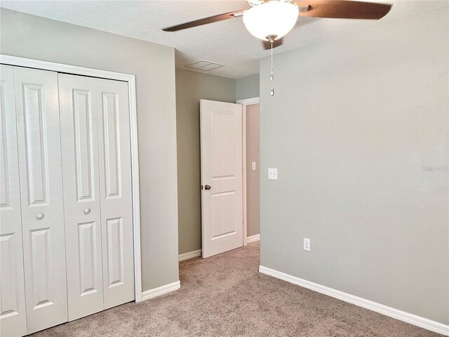 unfurnished bedroom with a closet, ceiling fan, and light colored carpet