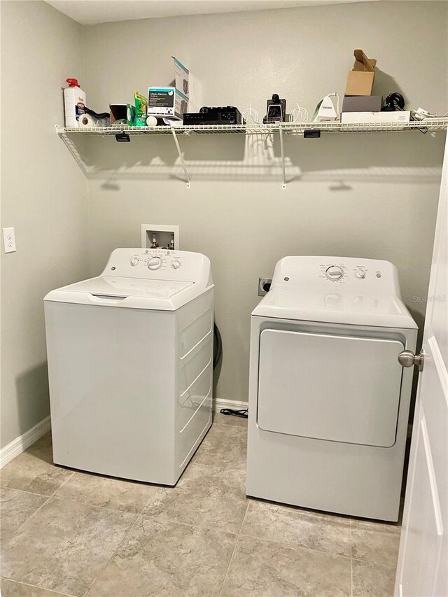 laundry area with washer and dryer and light tile patterned floors