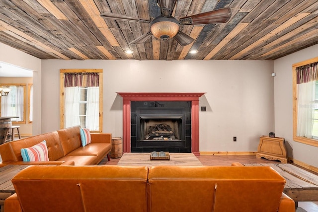 living room featuring ceiling fan, wooden ceiling, and a tiled fireplace