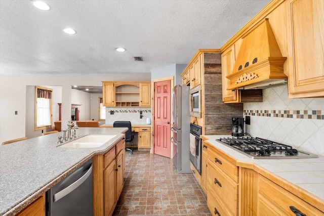 kitchen featuring appliances with stainless steel finishes, custom exhaust hood, tasteful backsplash, sink, and tile countertops