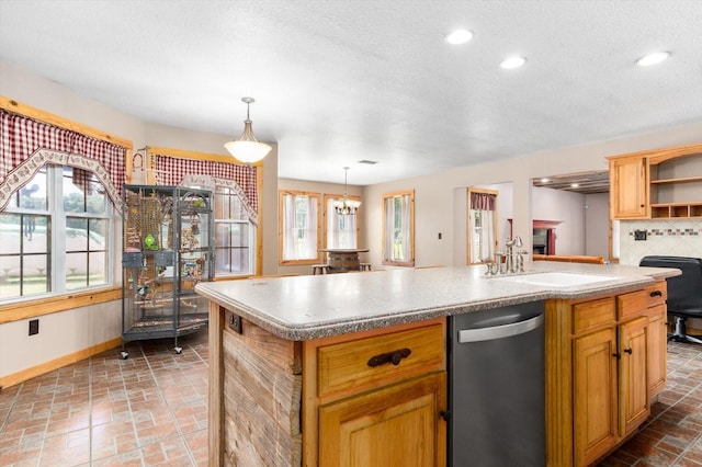 kitchen featuring a notable chandelier, pendant lighting, decorative backsplash, sink, and an island with sink