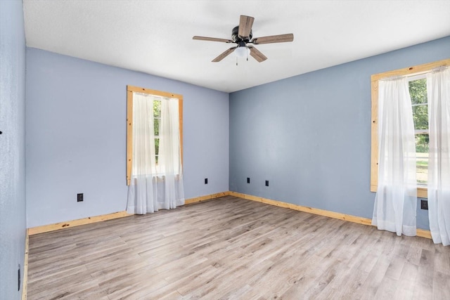 spare room featuring ceiling fan, light wood-type flooring, and a healthy amount of sunlight