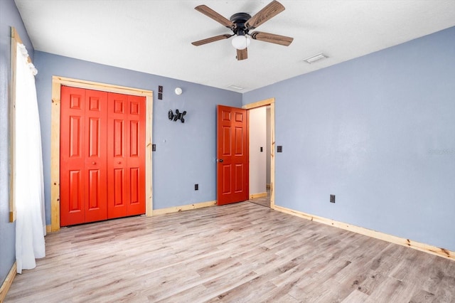 unfurnished bedroom featuring ceiling fan, a closet, and light wood-type flooring