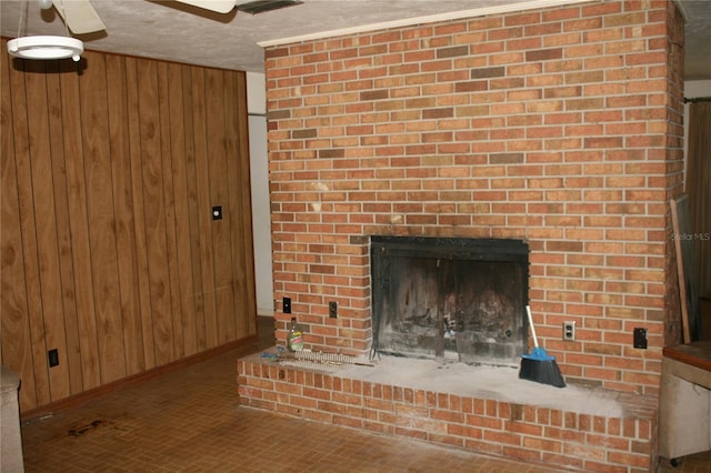 interior space with wood walls, brick wall, a fireplace, and ceiling fan