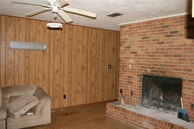 unfurnished living room featuring wood walls, a fireplace, ceiling fan, and a textured ceiling