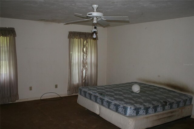 unfurnished bedroom with ceiling fan and dark carpet