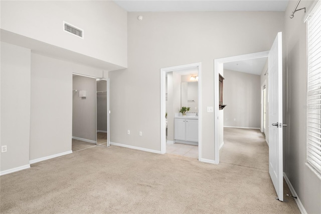 unfurnished bedroom featuring light colored carpet, connected bathroom, a closet, and a spacious closet