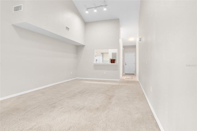 spare room with rail lighting, light carpet, and high vaulted ceiling