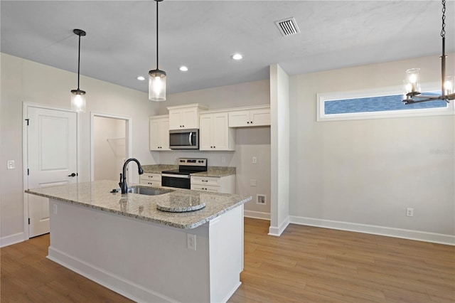 kitchen featuring a center island with sink, stainless steel appliances, light wood-style floors, white cabinetry, and a sink