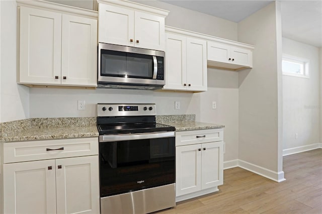 kitchen featuring light stone counters, stainless steel appliances, white cabinetry, baseboards, and light wood-type flooring