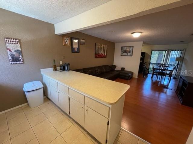 kitchen featuring kitchen peninsula, light tile patterned floors, and a textured ceiling