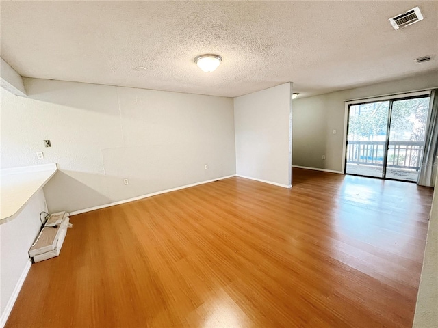 unfurnished room with hardwood / wood-style floors and a textured ceiling