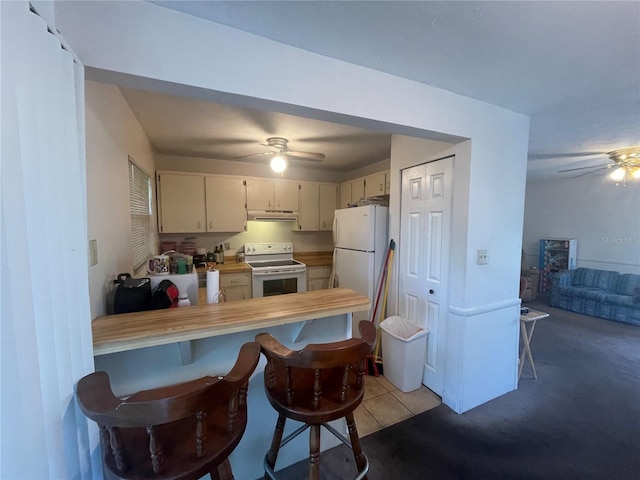 kitchen with a kitchen bar, white appliances, kitchen peninsula, and cream cabinetry