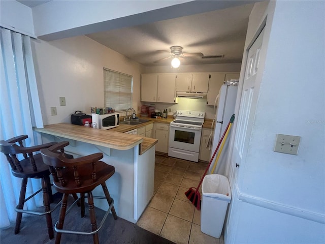 kitchen with kitchen peninsula, sink, white appliances, a kitchen breakfast bar, and light tile patterned floors