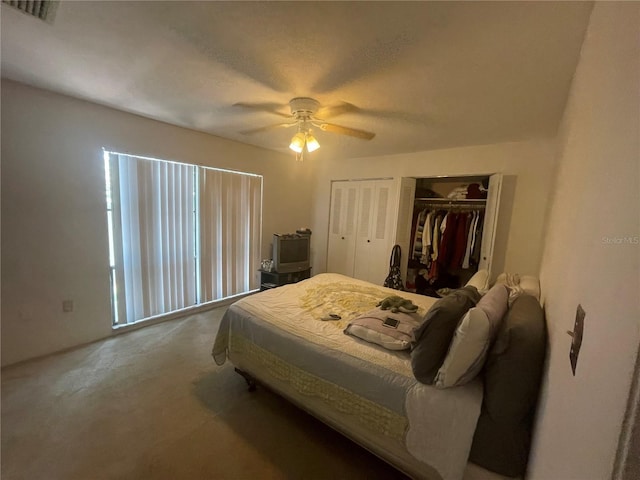 bedroom with ceiling fan, two closets, and carpet