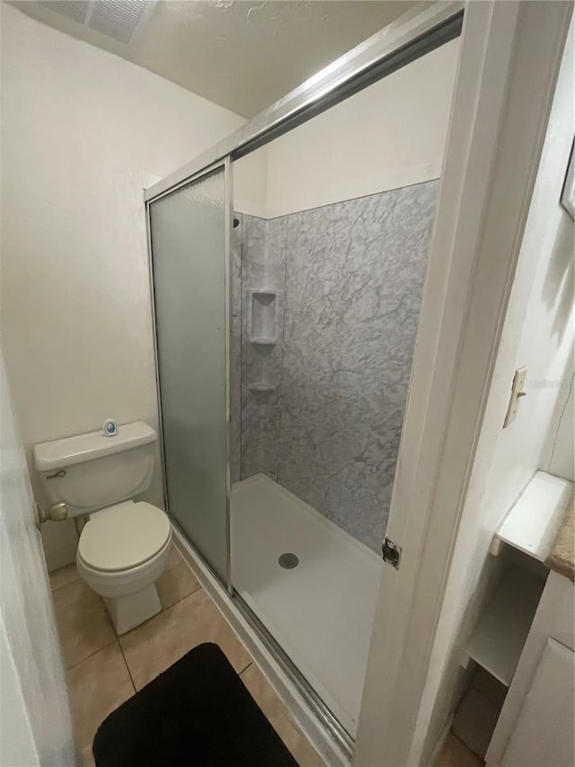 bathroom with toilet, tile patterned flooring, and walk in shower