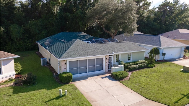 view of front of home featuring a garage, central AC, and a front lawn