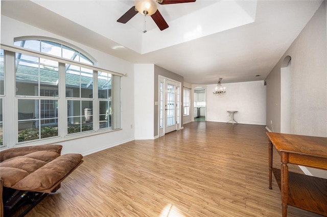 living room with ceiling fan with notable chandelier, light hardwood / wood-style floors, and plenty of natural light