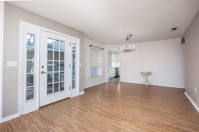 unfurnished room featuring light hardwood / wood-style flooring and a chandelier