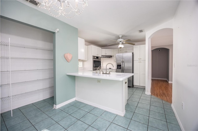 kitchen with light tile patterned floors, ceiling fan, appliances with stainless steel finishes, white cabinetry, and kitchen peninsula