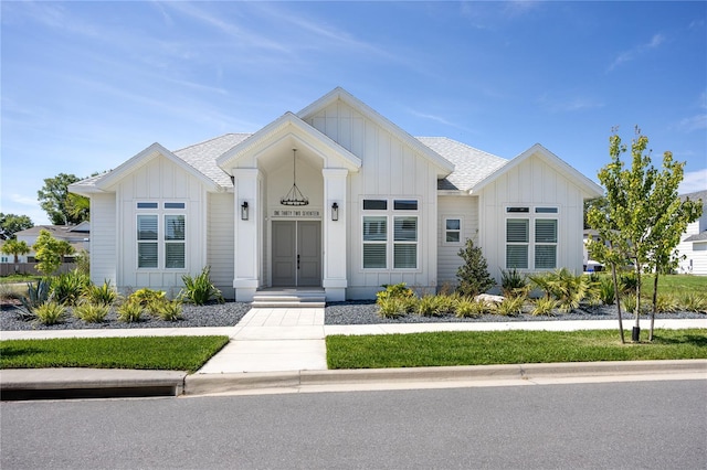 modern inspired farmhouse featuring board and batten siding and roof with shingles