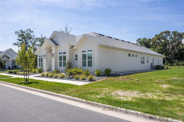 view of property exterior featuring a lawn, board and batten siding, and roof with shingles