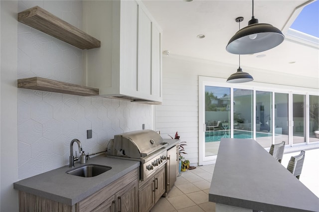 kitchen featuring light tile patterned flooring, sink, pendant lighting, and white cabinetry