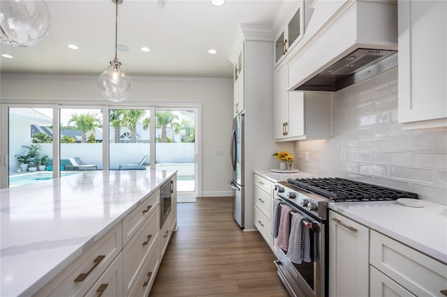 kitchen featuring white cabinetry, premium range hood, wood-type flooring, decorative backsplash, and appliances with stainless steel finishes