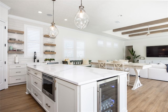 kitchen featuring white cabinetry, beverage cooler, light hardwood / wood-style floors, hanging light fixtures, and decorative backsplash