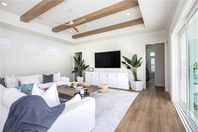 living room featuring a tray ceiling, light hardwood / wood-style flooring, ornamental molding, and ceiling fan