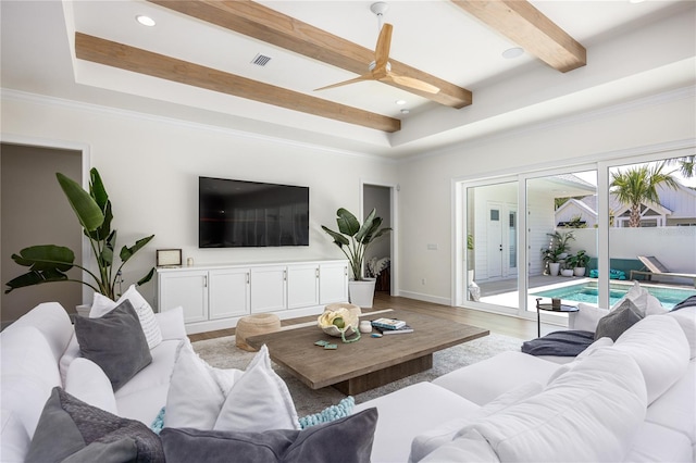 living room featuring beam ceiling, ceiling fan, light wood-type flooring, and a tray ceiling