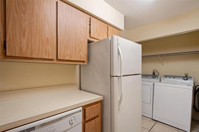 clothes washing area with light tile patterned floors and washer and clothes dryer