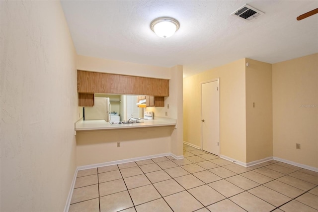 kitchen with sink, a breakfast bar area, light tile patterned floors, kitchen peninsula, and white appliances