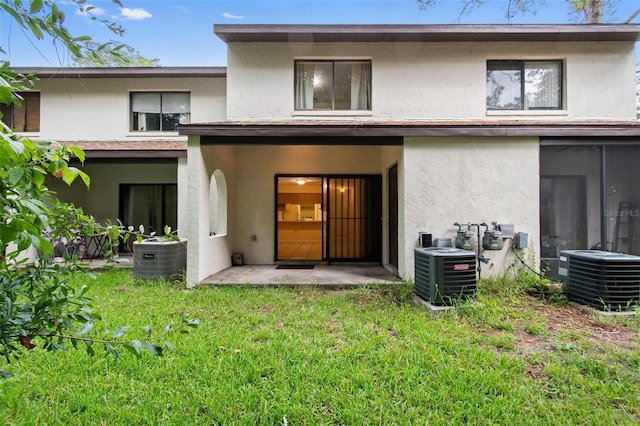 rear view of property with cooling unit and a lawn