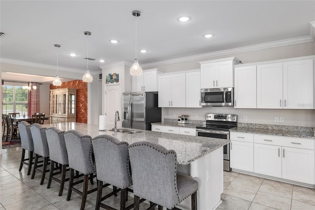 kitchen featuring hanging light fixtures, white cabinetry, a center island with sink, and stainless steel appliances