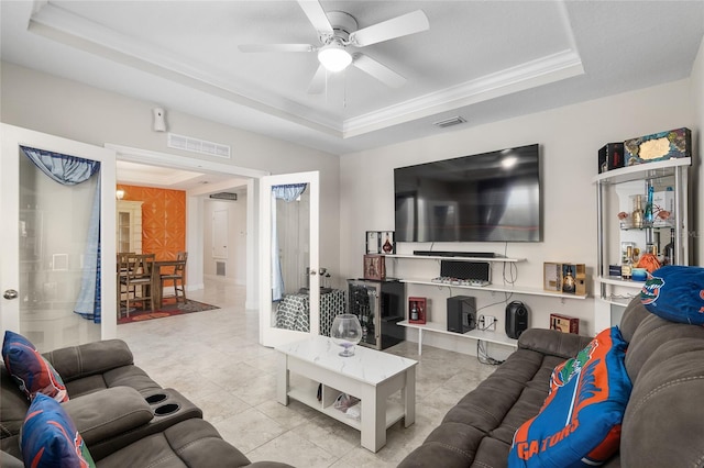 tiled living room featuring ceiling fan, crown molding, and a tray ceiling