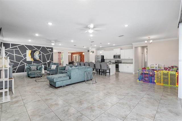 tiled living room with ceiling fan with notable chandelier and ornamental molding