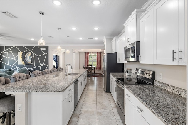 kitchen with a kitchen island with sink, stainless steel appliances, ornamental molding, and a breakfast bar