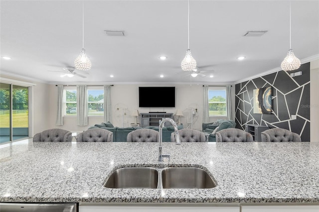 kitchen featuring ceiling fan, sink, light stone counters, and decorative light fixtures